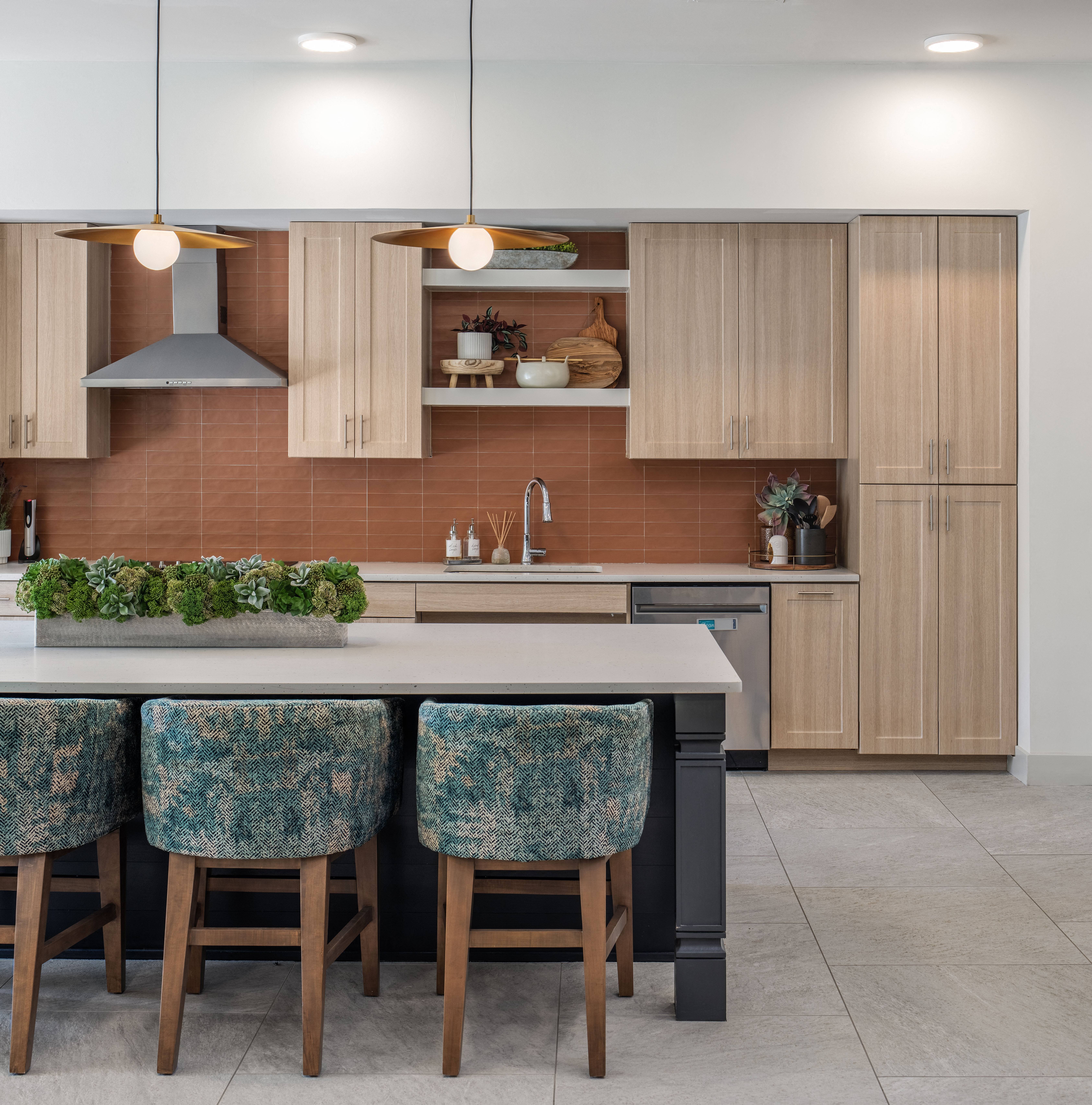 an open kitchen area with wooden cabinets and an island with chairs at a senior apartment community